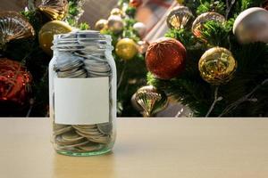 dinheiro na garrafa de vidro com desfoque de fundo de árvore de natal decorada foto