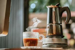 xícara de café com fundo de cafeteira moka vintage na mesa de madeira no escritório em casa foto