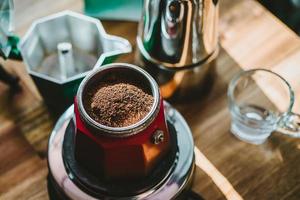 café moído finamente e cafeteira vintage moka pote na mesa de madeira em casa, foco seletivo. foto