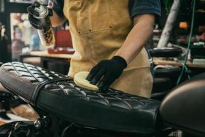 motociclista limpando motocicleta, polido e spray de cera de revestimento no assento. conceito de motocicleta de reparação e manutenção. foto