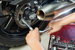 mecânico usando uma chave e soquete na roda dentada da motocicleta conceito de manutenção e reparo na garagem da motocicleta foco seletivo foto
