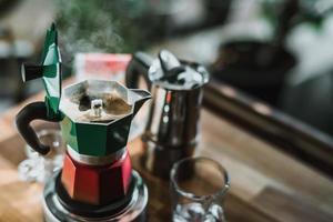 café quente no pote de moka no fogão elétrico, cafeteira vintage na mesa de madeira em casa, foco seletivo. foto