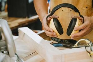 carpinteiro segurando protetores auriculares na oficina, fabricante de bricolage e conceito de marcenaria. foco seletivo foto