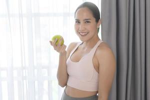 caber jovem comendo uma maçã depois de trabalhar em casa, esporte e conceito de estilo de vida saudável. foto