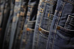 closeup muitos jeans pendurados em um rack. linha de calças jeans penduradas no armário. foto