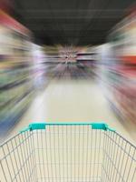 exibição de carrinho de compras de supermercado com desfoque de movimento do corredor do supermercado foto