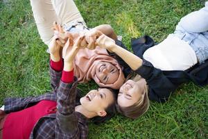 alegres diversas mulheres de mãos dadas enquanto estava deitado no gramado foto