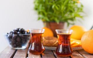 chá turco, bagel de gergelim, laranjas e azeitonas na mesa de madeira foto