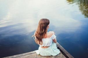 menina sentada à beira do rio foto