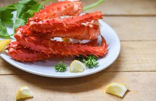 Pernas de caranguejo-real do Alasca cozinharam frutos do mar com especiarias de limão em um prato branco na mesa de madeira - hokkaido de caranguejo vermelho foto