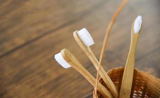 escova de dentes de bambu na cesta eco natural itens livres de plástico em fundo rústico - zero desperdício banheiro usar menos conceito de plástico foto