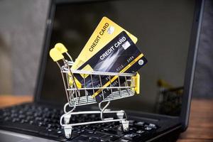 compras on-line com cartão de crédito no carrinho de compras no fundo do laptop para pagamento on-line em casa conceito foto