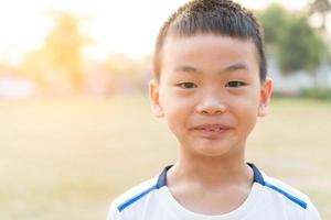 menino asiático com um sorriso no rosto de manhã, fundo de natureza turva. foto