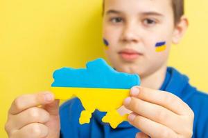 mapa da ucrânia em amarelo e azul nas mãos de um menino. ucrânia sem conceito de guerra foto