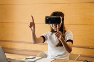 linda garota sorridente usa fone de ouvido vr e toque interativo pelo ar. dispositivo de óculos de fone de ouvido vr. controle de mulher de negócios asiáticos por realidade virtual. foto