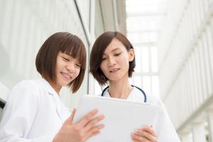 médicos asiáticos discutindo com tablet pc digital