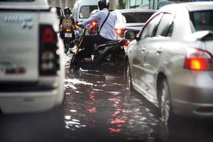 bangkok, tailândia, 16 de maio de 2019-inundação na via pública e motocicletas e minicaminhões no engarrafamento foto