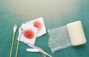 ferramentas médicas incluem tesouras, cotonetes, gaze de rolo de rede e gaze de sangue em vestido cirúrgico verde para ferida limpa foto