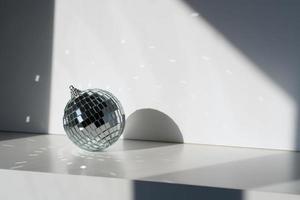 bola de discoteca à luz do sol no fundo branco foto