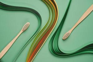 escovas de dentes de bambu em fundo verde com quilling foto