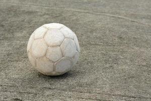 bola de futebol velha no chão de cimento foto