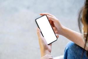 uma mulher segurando um telefone celular com uma tela branca em branco. o espaço em branco na tela branca pode ser usado para escrever uma mensagem ou colocar uma imagem.