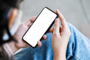 uma mulher segurando um telefone celular com uma tela branca em branco. o espaço em branco na tela branca pode ser usado para escrever uma mensagem ou colocar uma imagem. foto