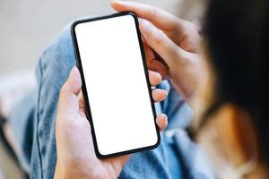 uma mulher segurando um telefone celular com uma tela branca em branco. o espaço em branco na tela branca pode ser usado para escrever uma mensagem ou colocar uma imagem. foto