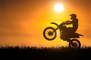 silhueta de uma motocicleta de motocross levantando a roda dianteira. conceitos de aventura e ação foto