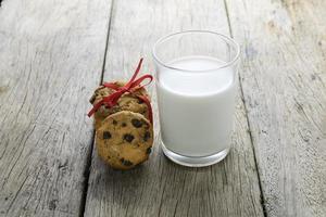 biscoitos e um copo com leite na mesa de madeira foto