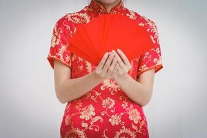 mulher asiática segurando envelope vermelho, mulher usa cheongsam, ano novo chinês foto