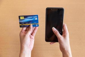 mulher segurando o cartão de crédito e smartphone. compras on-line na internet usando um smartphone foto