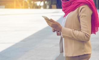 mulher muçulmana mensagens em um telefone celular na cidade foto