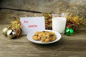 biscoitos e um copo com leite com uma nota branca para o Papai Noel foto