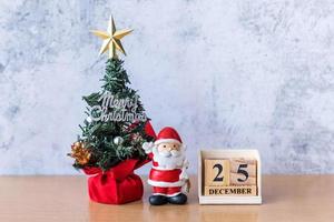 bloco calendário data 25 de dezembro calendário e decoração de natal - papai noel, árvore e presente na mesa de madeira. natal e feliz ano novo conceito foto
