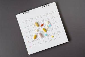 pílulas em um fundo de calendário. conceito de saúde foto