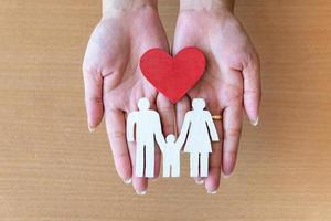 mãos de mulher segurando coração vermelho e família ícone, cuidados de saúde, conceito de seguro familiar foto