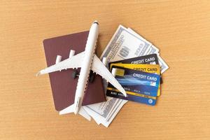 avião de brinquedo, cartões de crédito, dólares e passaporte na mesa de madeira. conceito de viagem foto