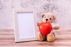 ursinho de pelúcia com porta-retrato na mesa de madeira. comemoração do dia dos namorados foto