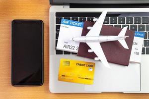smartphone perto de computador portátil e avião na mesa. conceito de reserva de bilhetes online foto