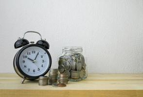 relógio e pilhas de moedas para o conceito de dinheiro de negócios foto