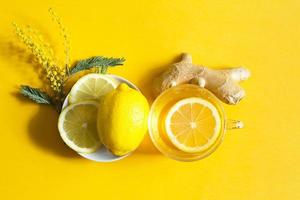 chá medicinal em uma xícara, gengibre, limão, acácia - fortalecer o sistema imunológico na estação fria - categoricamente. bebida vitamínica para saúde e ingredientes em fundo amarelo.
