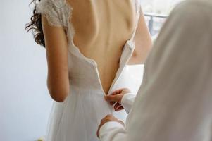 o noivo ajuda a prender o vestido à noiva. foto