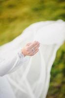 costureira abotoando o lindo vestido de noiva, elegante e de costas nuas. foto