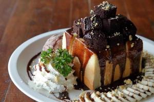 sorvete de chocolate mel torrada com mix de frutas fatiadas e chantilly servido na chapa branca sobre a mesa de madeira foto