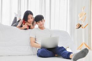 jovem casal trabalhando online em casa no quarto juntos durante a quarentena para nova política normal e de distanciamento social foto