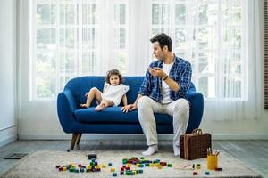 jovem pai atraente conversando com sua filha bonitinha depois de brincar com blocos de madeira, família feliz passando o fim de semana de lazer juntos foto