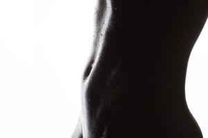 Figure.body atlética feminina e imprensa abdominal com água cai close-up em um fundo branco. foto