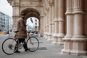 jovem segurando smartphone e andando com bicicleta. transporte ecologicamente correto. foto