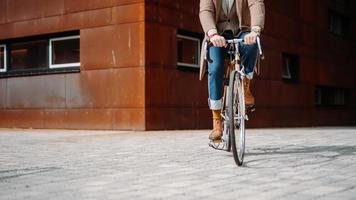 meio close-up tiro na perna de um empresário com bicicleta indo para o escritório. construção moderna. copyspace